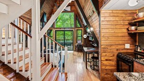 A wooden interior with a staircase, a dining area, and a kitchen. - NEW! Creekside Ranch A-Frame (Young Harris)