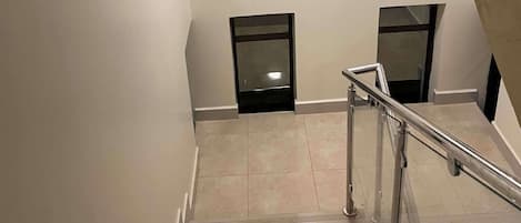 A multi-level interior with a staircase, metal handrails, and a tiled floor.