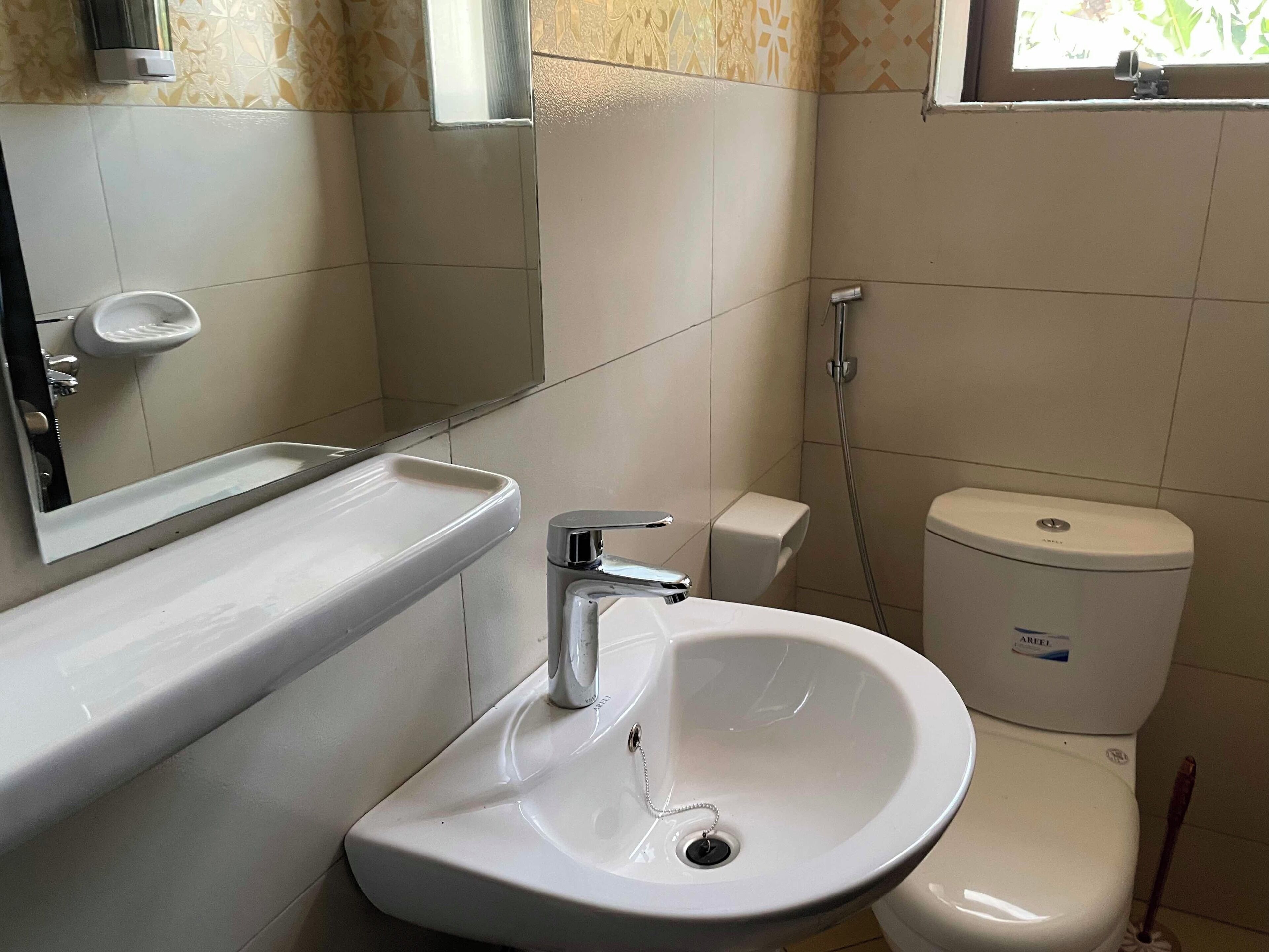 A bathroom with a white sink, a mirror, a toilet, and a shower.