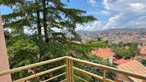 A balcony with a metal railing overlooking a residential area with trees and houses. - Kampala (Kampala)