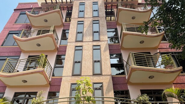 A multi-story building with balconies, large windows, and potted plants. - Kampala (Kampala)