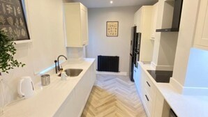 Une cuisine moderne avec des meubles blancs, un parquet en bois disposé en chevrons et un four encastré.