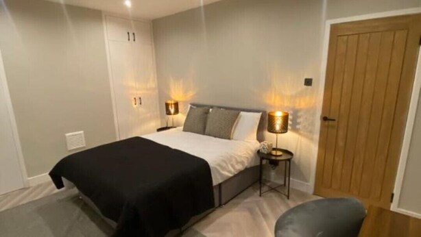 Une chambre à coucher avec un lit, des lampes de chevet, un bureau et une chaise.
