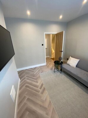 Relax and unwind in this stylish living space, featuring a large flat-screen TV, comfortable sofa, and cozy rug.