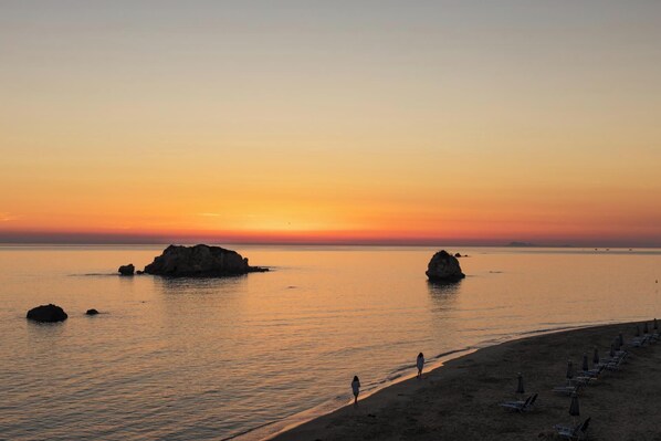 A beach with a sunset, calm sea, and rocky outcrops. - Uranos - Two Bedroom Villa, Sleeps 4 (Corfu)