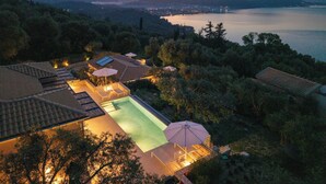 A resort with a swimming pool, outdoor seating, and a view of a lake and mountains. - Uranos - Two Bedroom Villa, Sleeps 4 (Corfu)