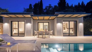 Een modern huis met een zwembad, grote schuifpuien en een patio.