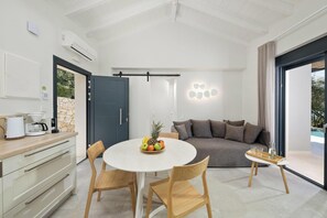 Una sala de estar moderna con una mesa de comedor redonda, sillas de madera, un sofá gris y una mesa de centro de vidrio.