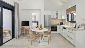 Een moderne keuken met witte kasten, een roestvrijstalen koelkast en een eethoek met een ronde tafel en houten stoelen.