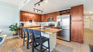 Une cuisine moderne avec des meubles en bois, des appareils en acier inoxydable et un îlot central doté de tabourets de bar.