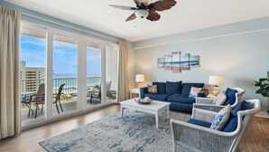 Un salon spacieux avec balcon, ventilateur de plafond, ensemble de canapés et vue sur l’océan.