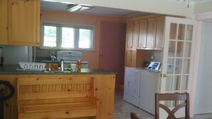 Una cucina compatta con mobili in legno, forno a incasso e un'area pranzo con tavolo e sedie.