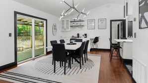A modern kitchen with a dining area, featuring a large window, a chandelier, and a black and white striped rug. - Adventure Coast Modern; 3/3 Pool w/ Firepit, Fenced, Heated Pool (Spring Hill)