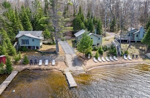 A lakeside cabin complex with multiple buildings, a dock, and a row of sun loungers.