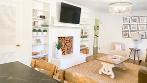 A living room with a fireplace, television, and a dining area with a table and chairs. - Luxury SouthPark Villa • 3BR • Spa Tub • Chef’s Kitchen • Near Dining & Uptown (Charlotte)