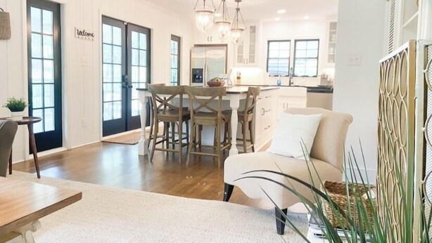 A spacious living area with a dining table, a sofa, and a kitchen in the background. - Luxury SouthPark Villa • 3BR • Spa Tub • Chef’s Kitchen • Near Dining & Uptown (Charlotte)