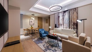 Una sala de estar moderna con un sofá, sillones, una mesa de centro y un televisor.
