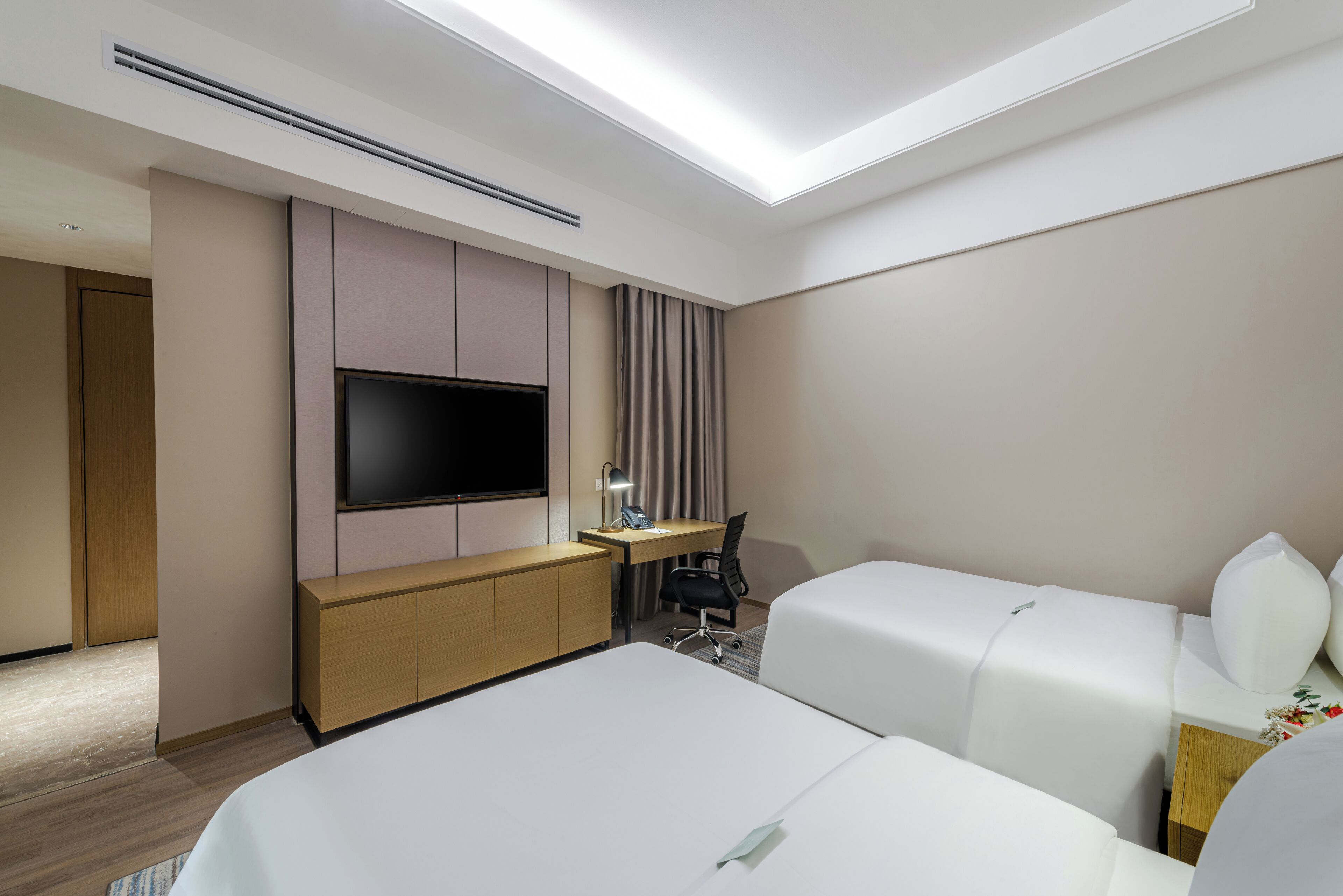 A hotel room with a bed, a desk, a chair, a TV, and a window.