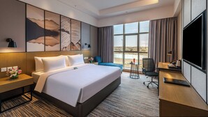Una habitación de hotel con una cama grande, un escritorio, una silla, un televisor y una ventana con vistas al desierto.