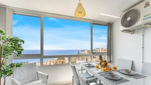 A balcony with a table set for breakfast, a potted plant, and a view of the sea. - Coastal Charm: Renovated 2-Bed Apt, Pool, Sea Views REF056 (Benalmádena)