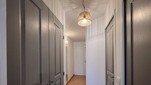 A hallway with two doors on each side, a patterned ceiling, and a hanging light fixture. - Charmant 2 Pièces Avec Jardinet (les issambres)