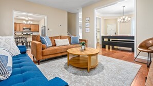 Ein Wohnzimmer mit einem blauen Sofa, einem Holztisch und einer Küche im Hintergrund.