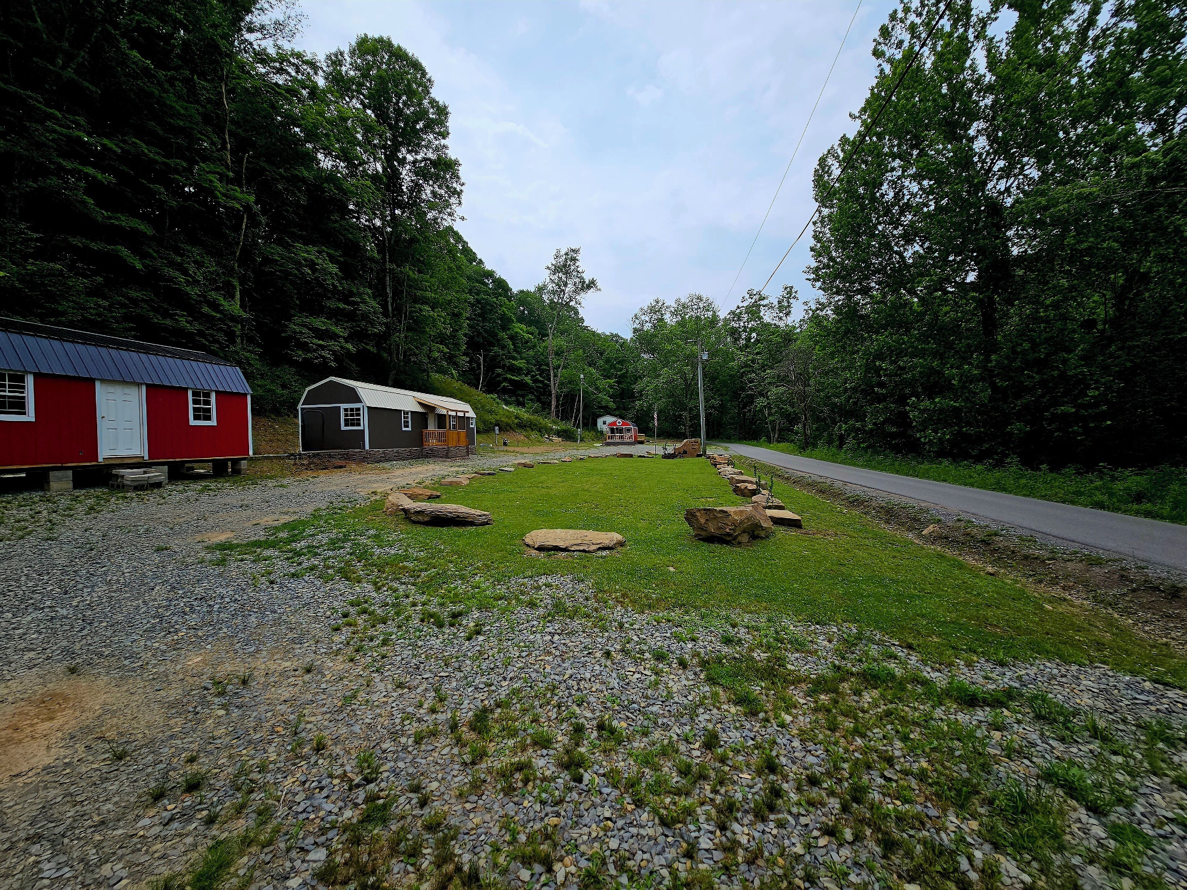 A red building with a white door and windows, a gravel path, and a grassy area with rocks.