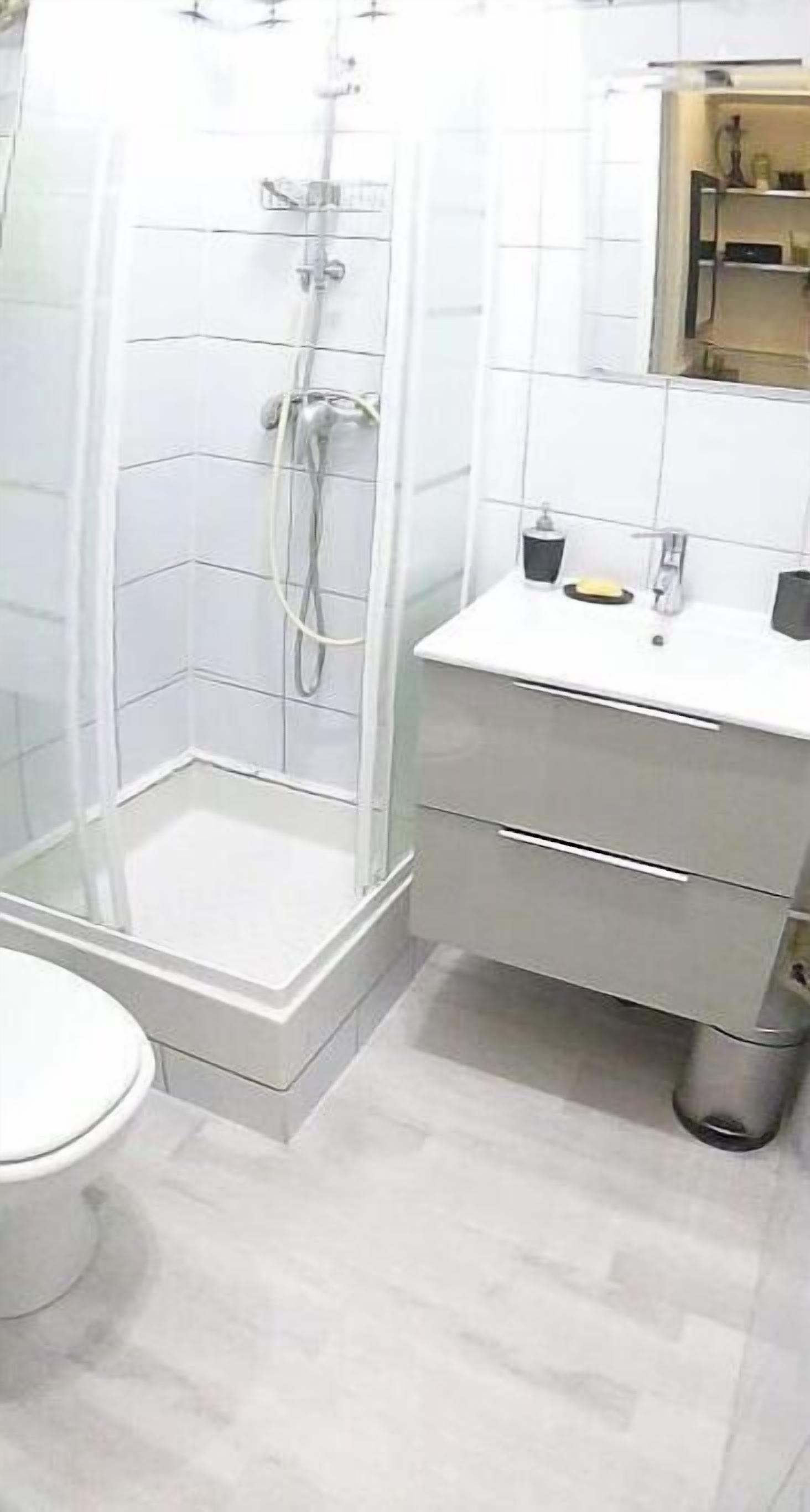 A modern bathroom with a glass-enclosed shower, a white sink with a mirror, and a toilet.