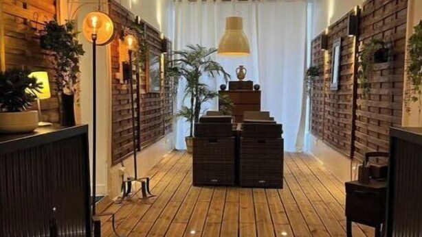 Een hal met houten vloer, een centrale trap en muren versierd met baksteenmotieven en planten.