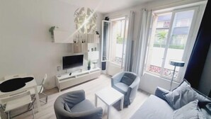 Een moderne, goed verlichte kamer met een bed, een televisie, een bureau en een stoel.