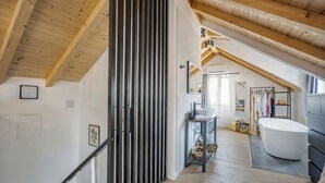 A modern bathroom with a freestanding bathtub, wooden beams, and a staircase leading to an upper level. - Studio apartments Yucca 2min to the sea (Trogir)