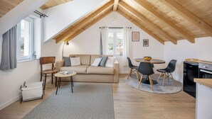 A cozy loft-style room with a high ceiling, a sofa, a dining table, and a kitchen area. - Studio apartments Yucca 2min to the sea (Trogir)