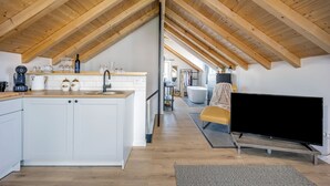 A modern loft-style kitchen with wooden beams, a central island, and a flat-screen TV. - Studio apartments Yucca 2min to the sea (Trogir)