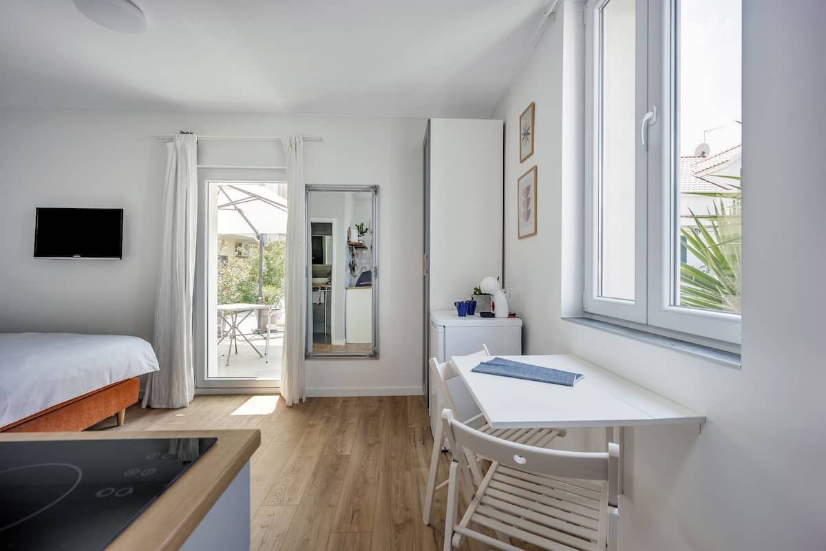 A modern bedroom with a bed, a desk, and a dining table.