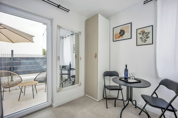 A room with a sliding glass door leading to an outdoor area with chairs and a table. There are two framed artworks on the wall and a mirror above the table. - Studio apartments Yucca 2min to the sea (Trogir)