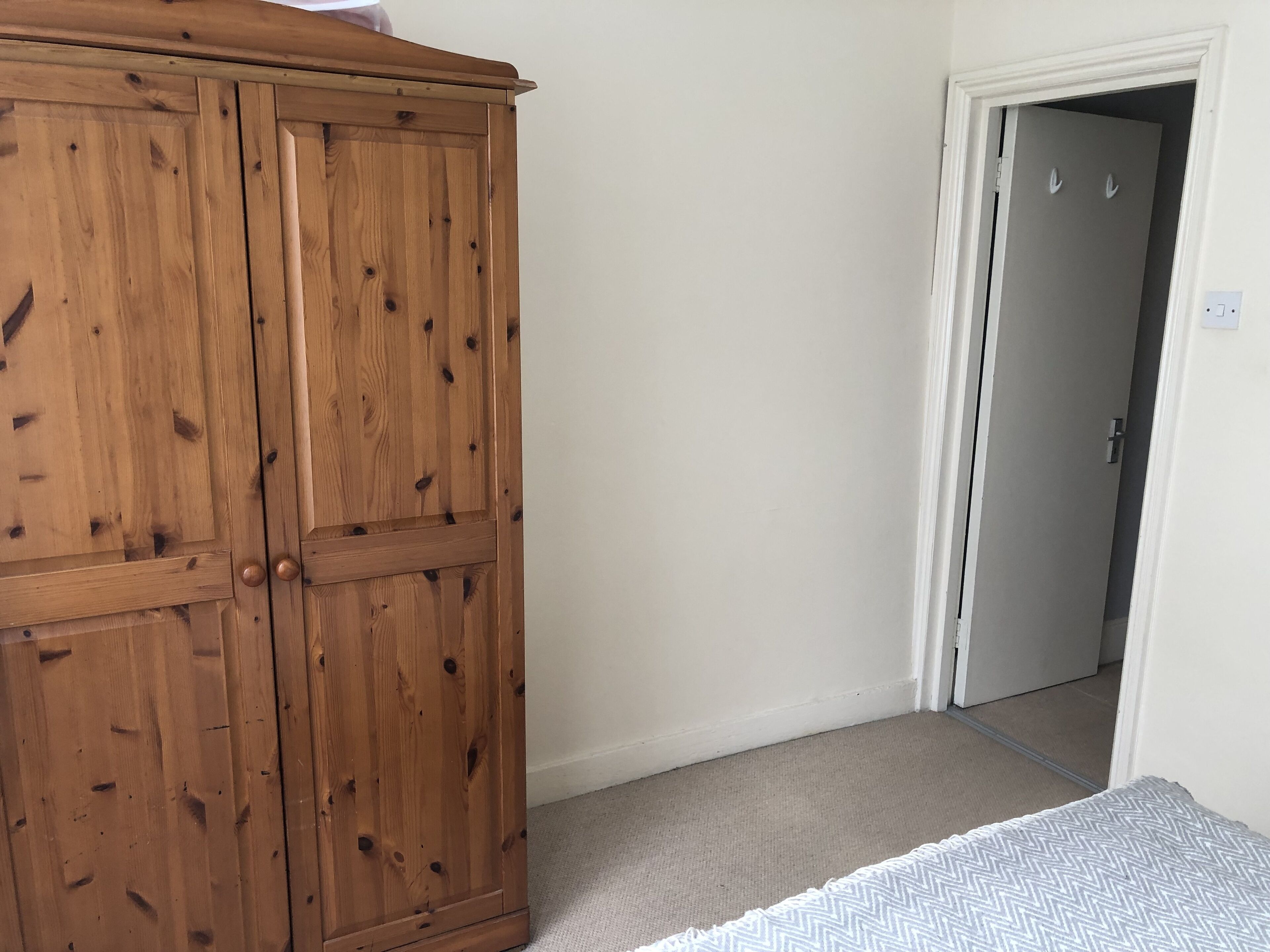 Ein Schlafzimmer mit einem Holzschrank, einer grauen Tür und einem Teppichboden.