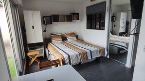 A compact bedroom with a single bed, a small table, and a chair. There is a wardrobe and a television on a stand. - Studio/cabine "Les Corsaires" (Berck)