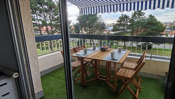 A balcony with a wooden table and chairs, a small rug, and a view of the neighborhood. - Studio/cabine "Les Corsaires" (Berck)