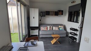 A modern living room with a grey sofa, a wooden coffee table, and a TV mounted on the wall. - Studio/cabine "Les Corsaires" (Berck)