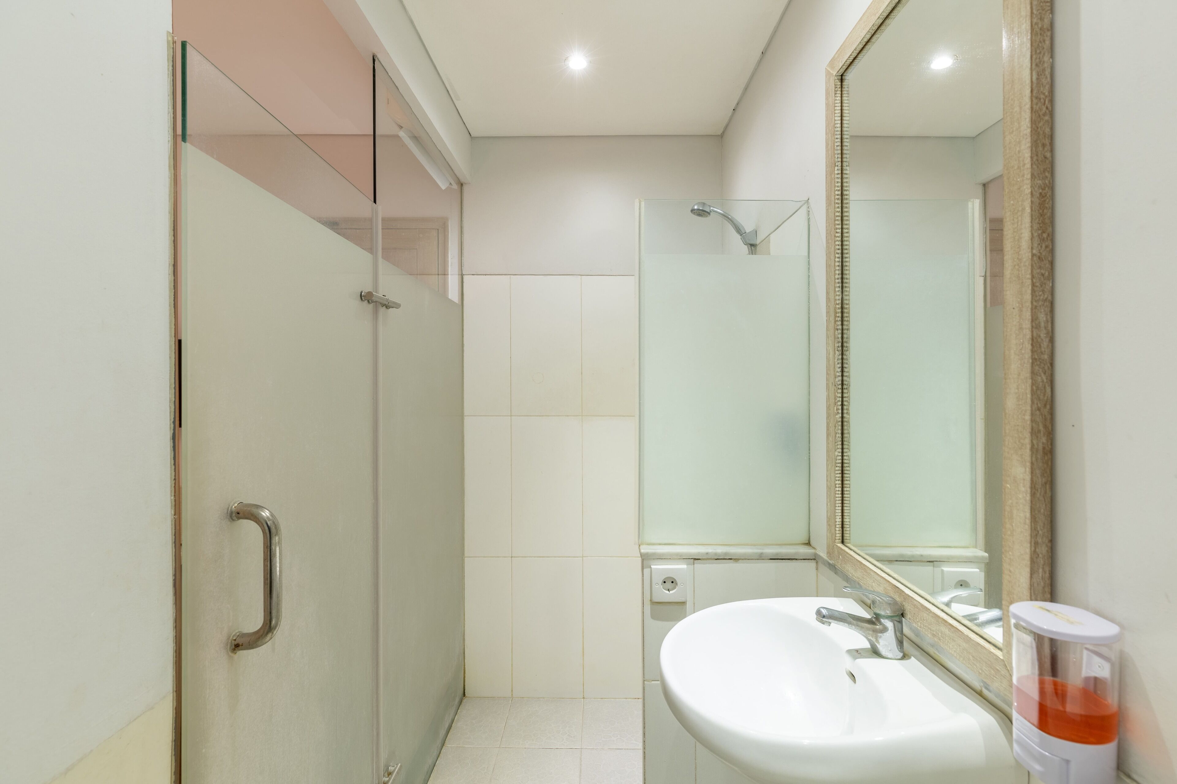 A modern bathroom with a glass shower enclosure, a white sink, and a large mirror.
