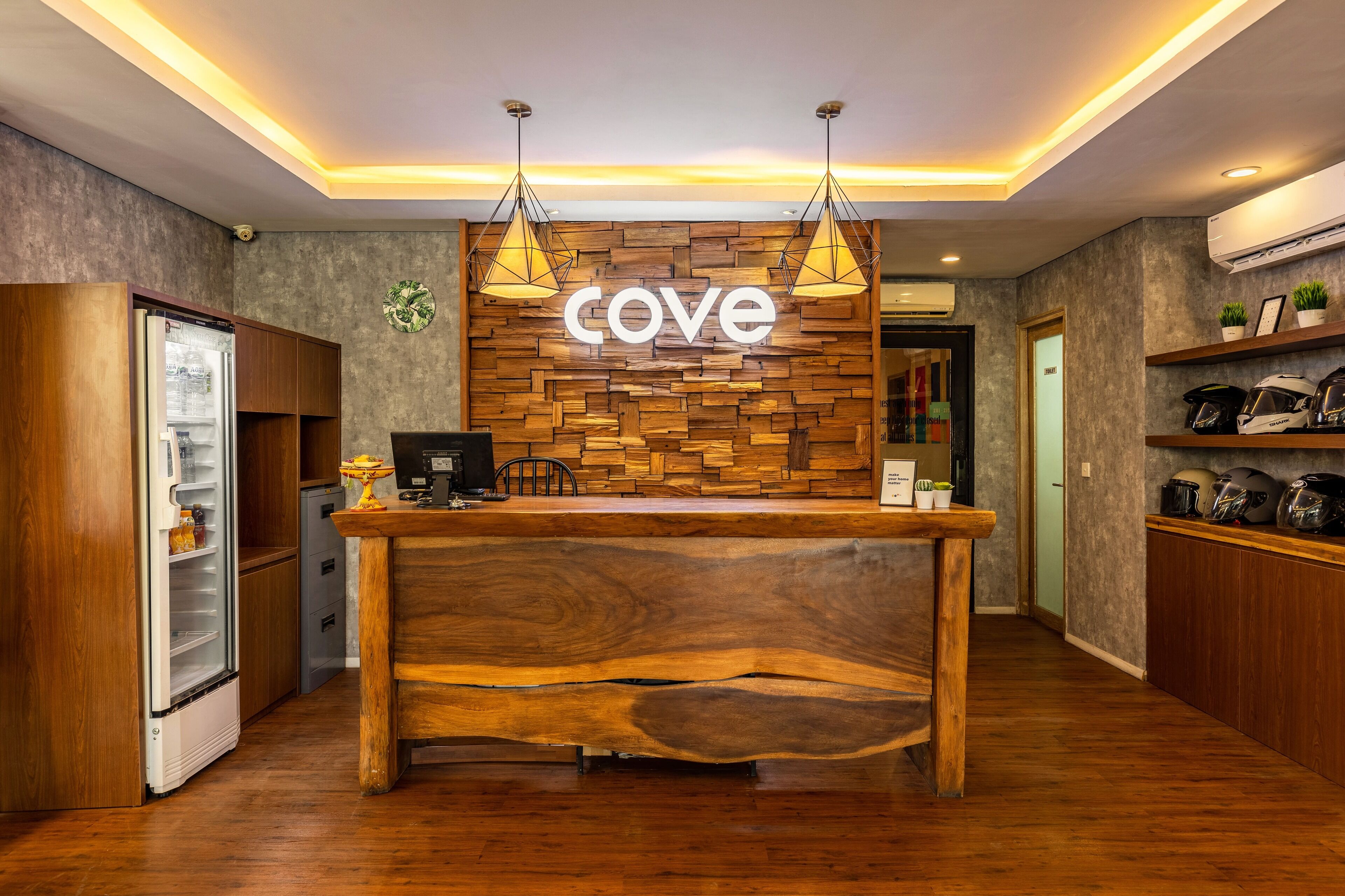 Una recepción con diseño de madera, un letrero que dice 'cove' y una cocina moderna con electrodomésticos y estantes.