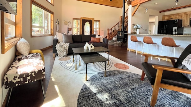 Ein geräumiges Wohnzimmer mit hohen Decken, einem gemütlichen Kamin und einer Küchenzeile mit Barhocker.
