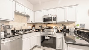 Een moderne keuken met witte kasten, roestvrijstalen apparatuur en een zwart aanrecht.