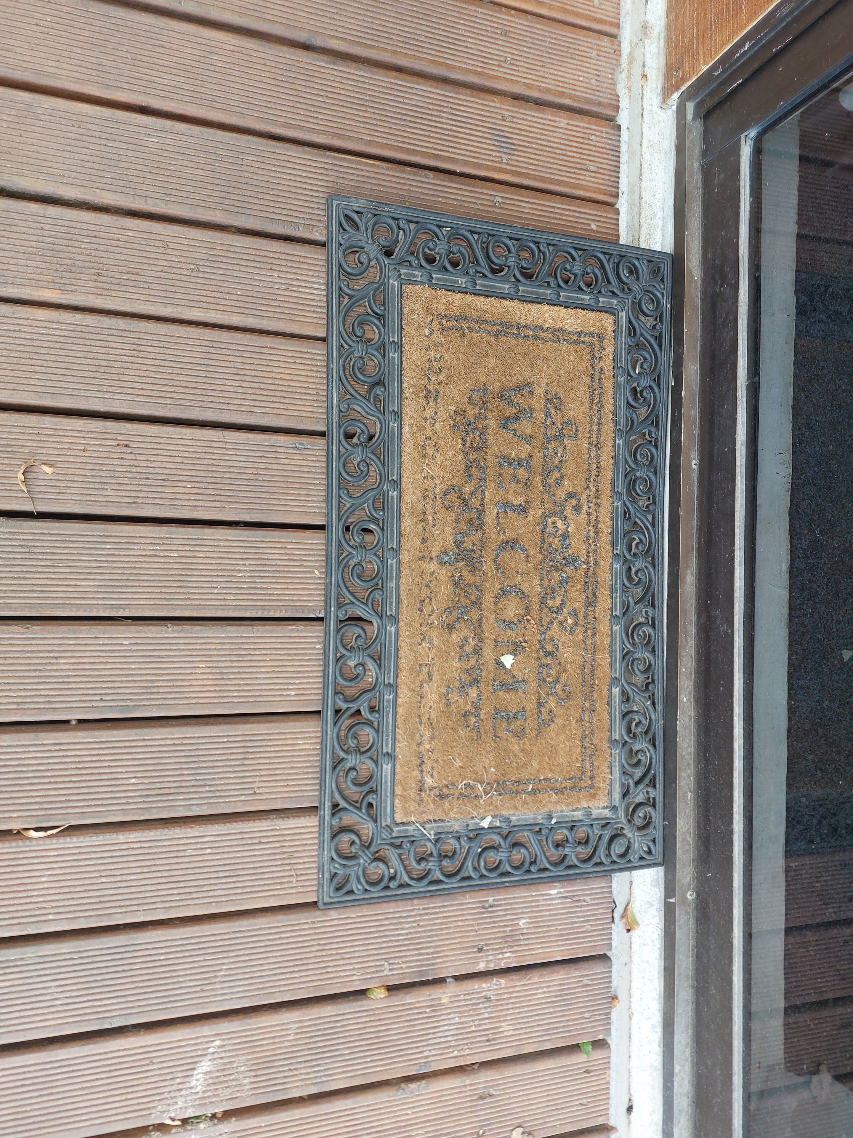 Een houten gevelwand met een decoratief metalen plaquette.