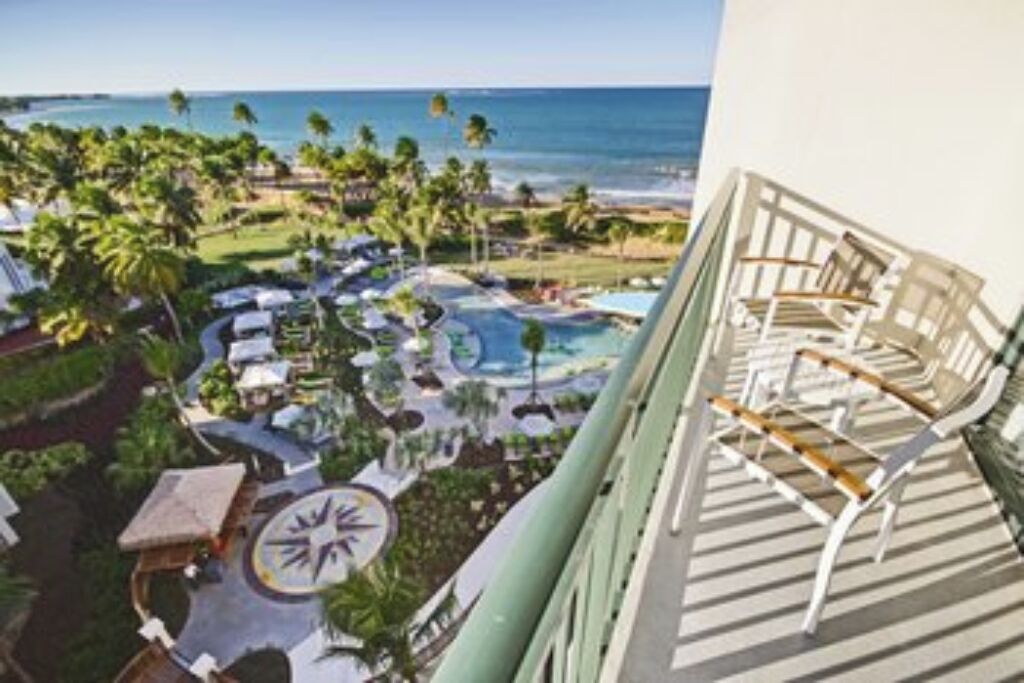 A resort with a pool, lounge chairs, and a view of the ocean.