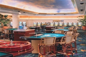 A casino with roulette tables, slot machines, and bar seating.