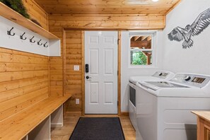 A laundry room with wooden walls, a white door, and two washing machines.