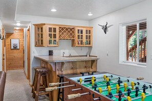 Una cocina con armarios de madera, un lavamanos y una mesa de futbolín.