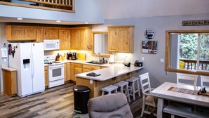 A spacious kitchen with wooden cabinets, a white refrigerator, and a dining area with a table and chairs.