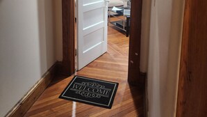 A hallway with a wooden door frame, a white door, and a welcome mat. - Downtown and secluded (Manchester)